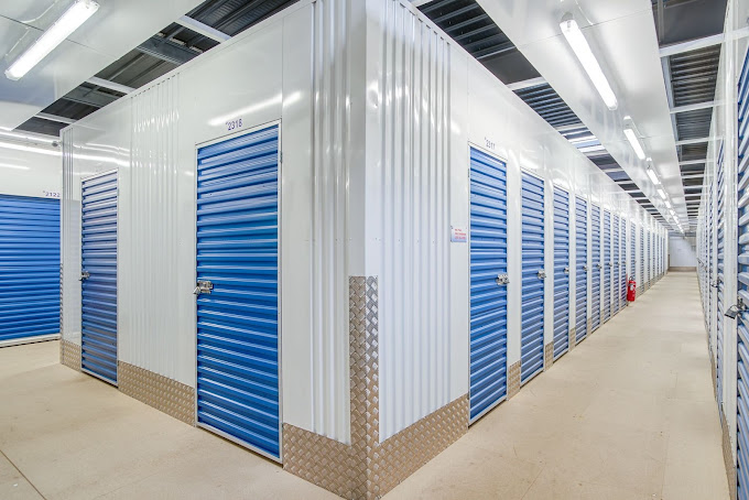 Allées et rangées de casiers de stockage avec portes bleues, ambiance intérieur clair et ordonné. Inclut le mot-clé: check-list déménagement.
