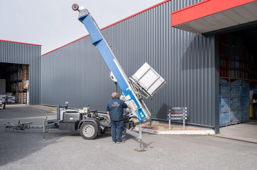Chariot élévateur bleu déployé à côté d’un entrepôt pour déplacer des cartons lourds, opérateur à l’avant.