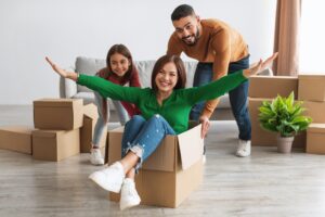 Famille souriante avec des boîtes en carton, état joyeux, fête du déménagement et pilier de rires, prête pour la chronologie des étapes d'un déménagement.